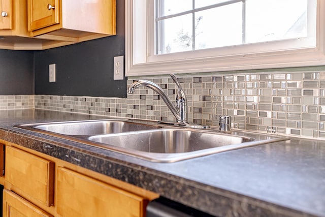 kitchen with dark countertops, a sink, and backsplash