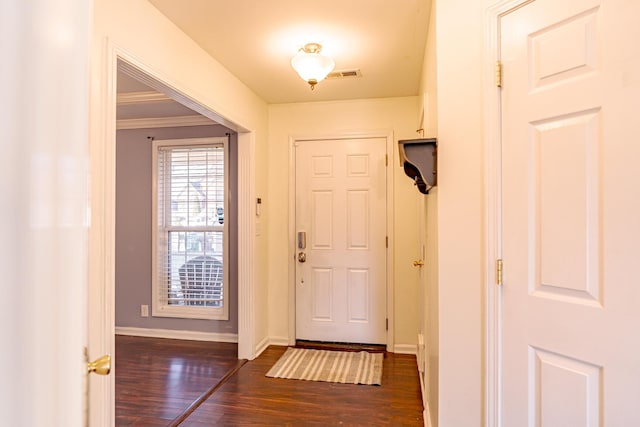 foyer with baseboards, crown molding, visible vents, and dark wood-type flooring