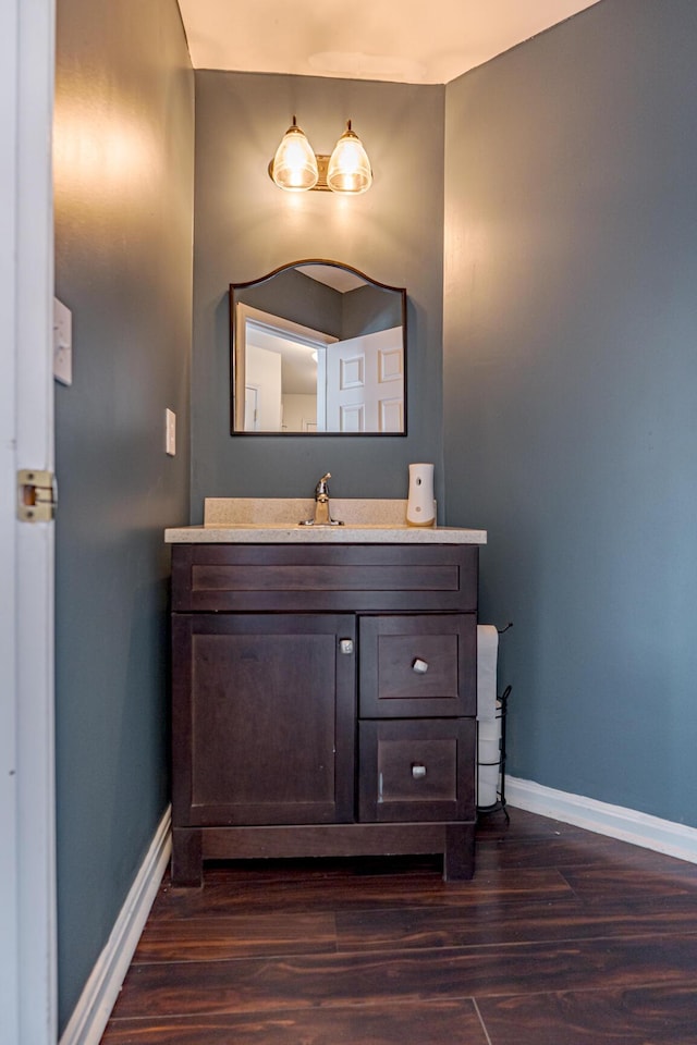 bathroom with baseboards, wood finished floors, and vanity