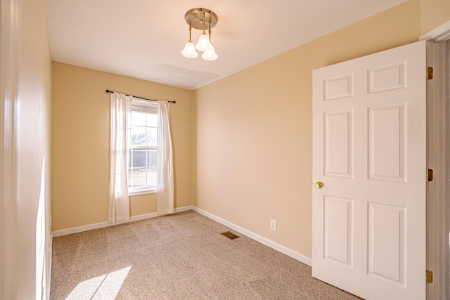 empty room with carpet flooring, visible vents, and baseboards