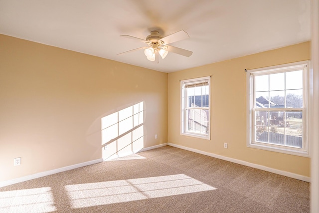 carpeted empty room with a ceiling fan and baseboards