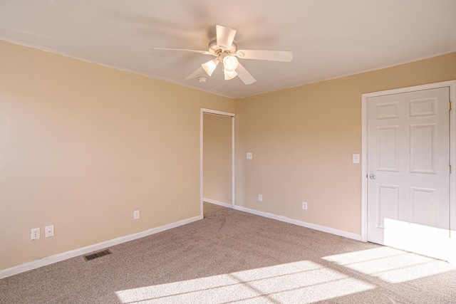 unfurnished room with carpet floors, baseboards, visible vents, and a ceiling fan