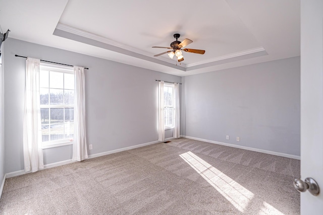 unfurnished room with a tray ceiling, carpet flooring, a ceiling fan, and baseboards