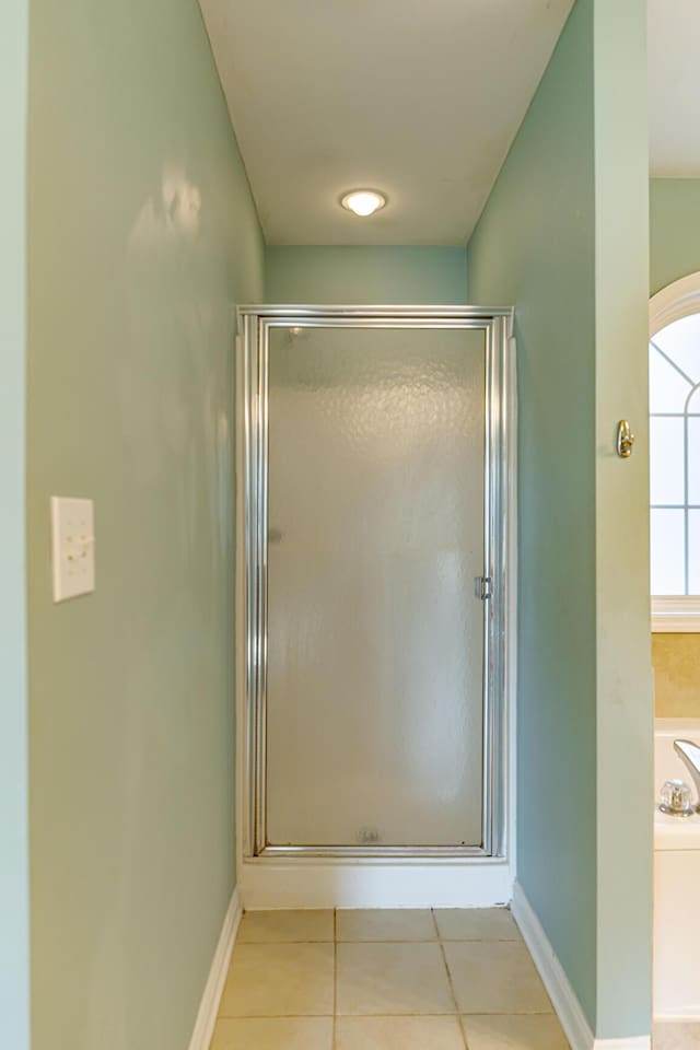 bathroom featuring a stall shower, a garden tub, baseboards, and tile patterned floors