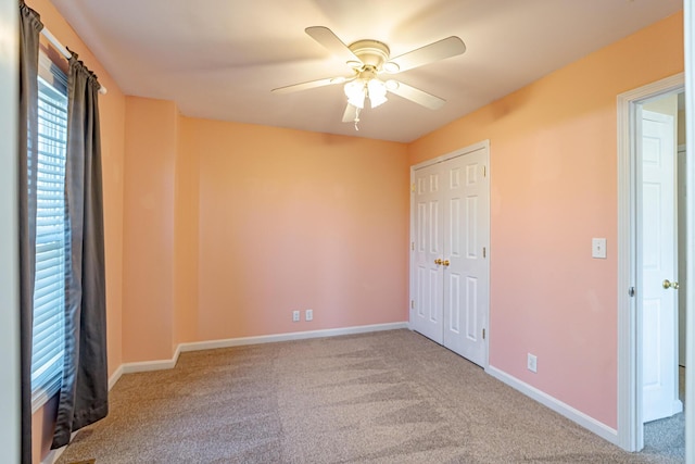 unfurnished bedroom with ceiling fan, a closet, carpet, and baseboards