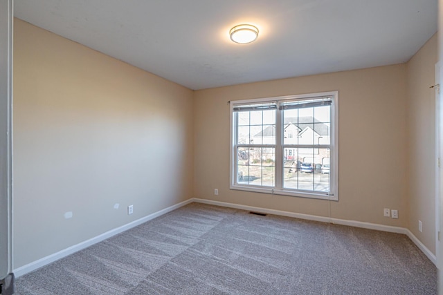 empty room with carpet floors, visible vents, and baseboards