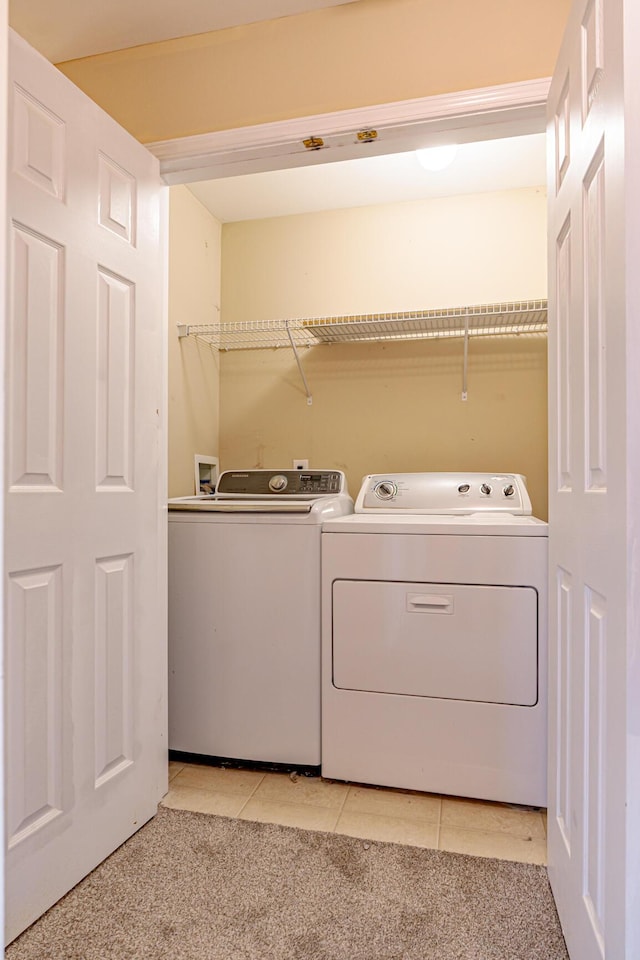 laundry room with laundry area, light tile patterned floors, light colored carpet, and washing machine and clothes dryer