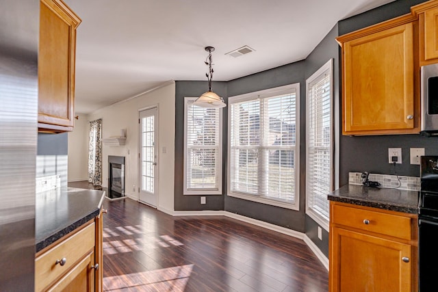 kitchen with dark wood-style floors, decorative light fixtures, visible vents, a glass covered fireplace, and baseboards