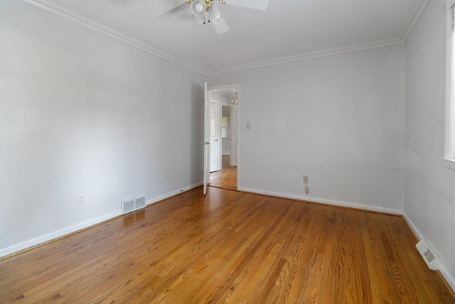 empty room with ornamental molding, baseboards, visible vents, and light wood finished floors