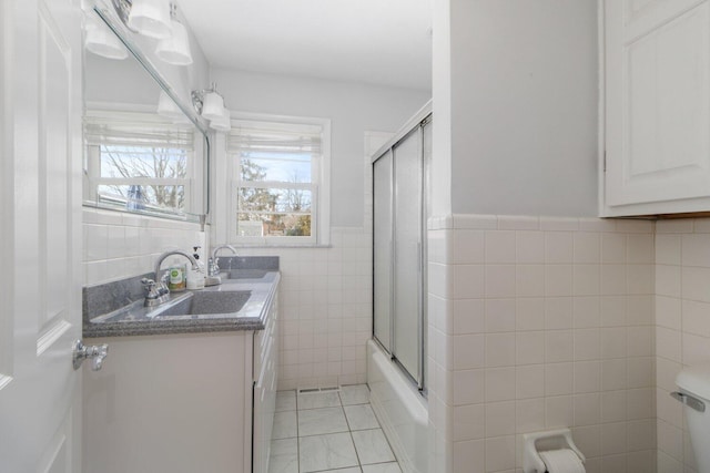 bathroom with wainscoting, toilet, tile patterned floors, vanity, and tile walls