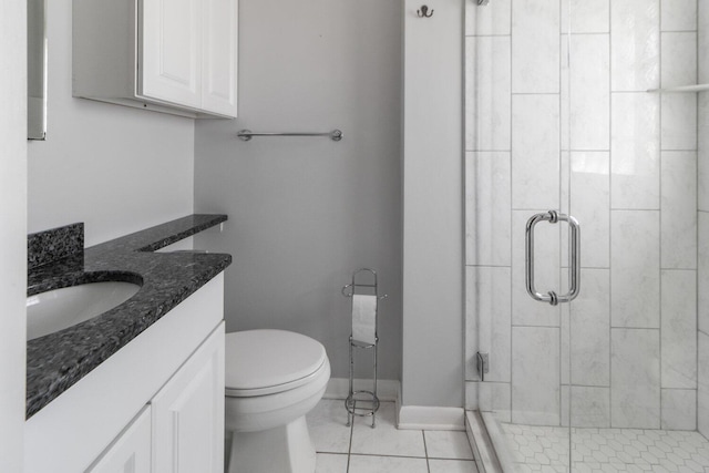 bathroom with tile patterned flooring, toilet, vanity, baseboards, and a stall shower