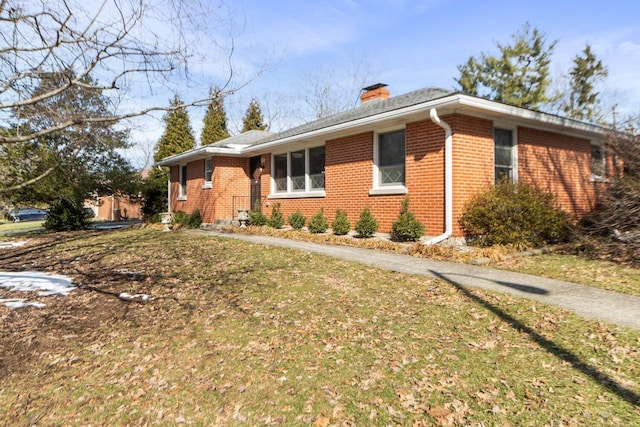 single story home with brick siding, a chimney, and a front lawn