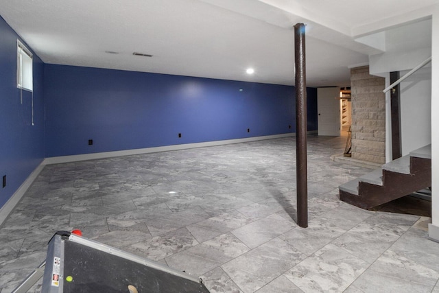 finished basement with stairway, visible vents, and baseboards