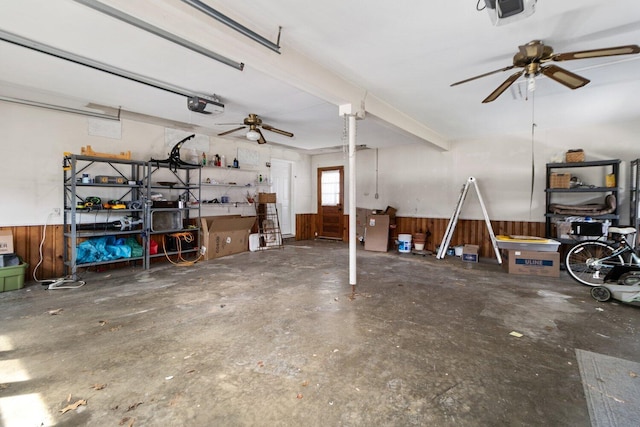 garage with ceiling fan, wood walls, wainscoting, and a garage door opener