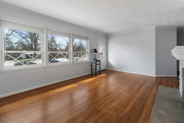 unfurnished room with a fireplace with flush hearth, crown molding, baseboards, and wood finished floors