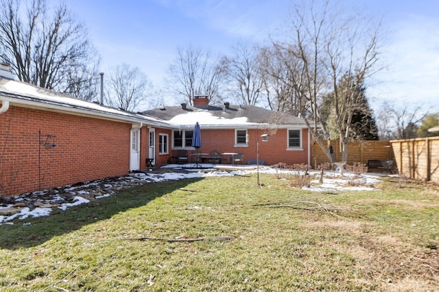 back of property with a patio, brick siding, fence, a lawn, and a chimney