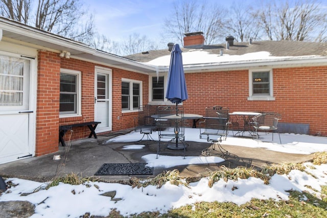 rear view of property with a patio area, brick siding, and a chimney