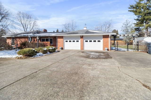 ranch-style house featuring a garage, concrete driveway, brick siding, and fence