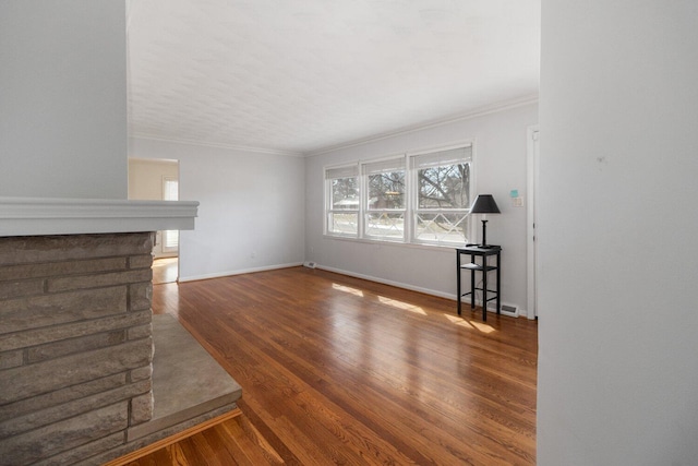 unfurnished living room with baseboards, wood finished floors, and crown molding