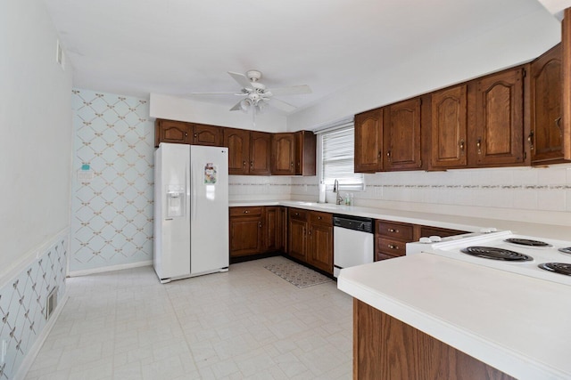 kitchen featuring white appliances, a sink, light countertops, light floors, and wallpapered walls