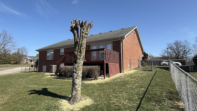 view of side of property featuring brick siding, a lawn, central AC, a deck, and a fenced backyard