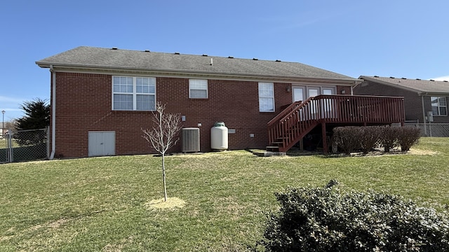 rear view of house featuring brick siding, a yard, and fence