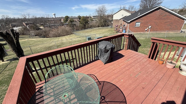 deck featuring a fenced backyard, outdoor dining area, and a lawn