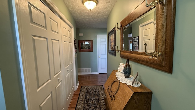 doorway to outside with baseboards, visible vents, dark wood-style flooring, and a textured ceiling