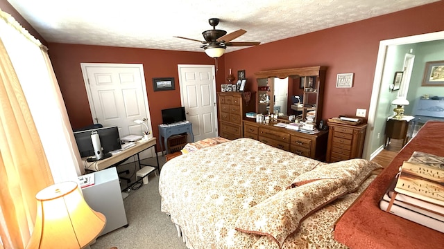 carpeted bedroom featuring a ceiling fan and a textured ceiling