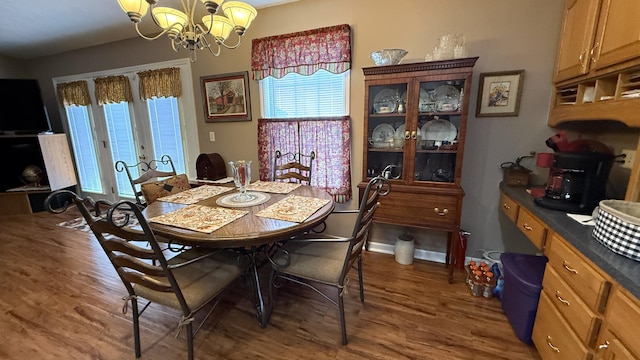 dining area with french doors, an inviting chandelier, and wood finished floors