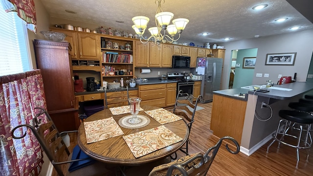 kitchen featuring a textured ceiling, a notable chandelier, stainless steel appliances, light wood-style floors, and open shelves