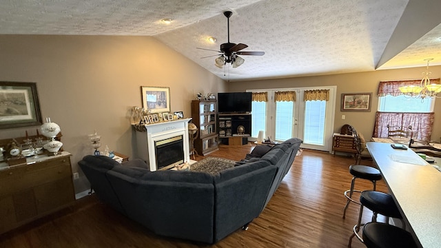 living room featuring lofted ceiling, wood finished floors, a textured ceiling, and a glass covered fireplace