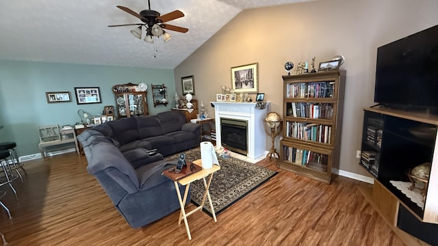 living area featuring lofted ceiling, a fireplace, baseboards, and wood finished floors