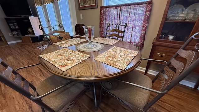 dining area with french doors, wood finished floors, a wealth of natural light, and baseboards