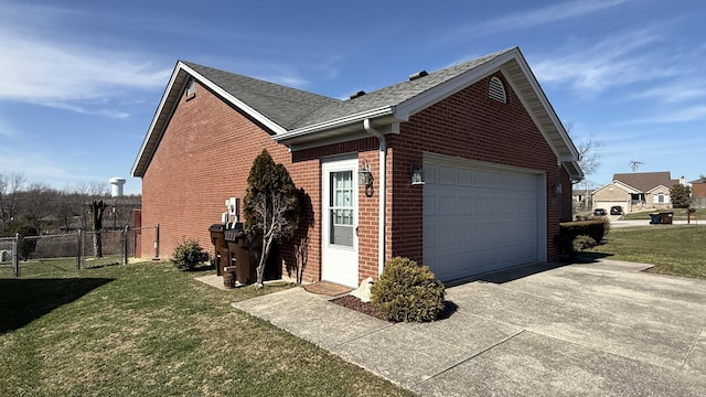 view of property exterior featuring concrete driveway, roof with shingles, fence, a yard, and brick siding