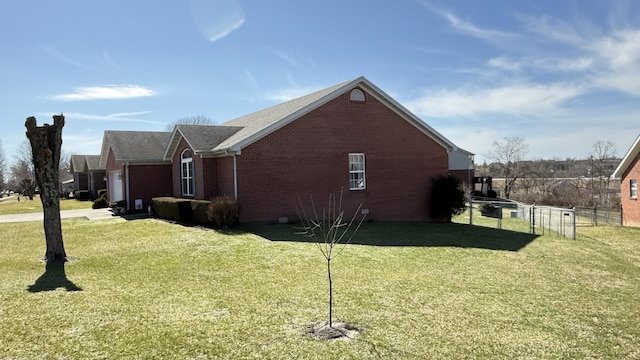 view of home's exterior with a yard, fence, and brick siding