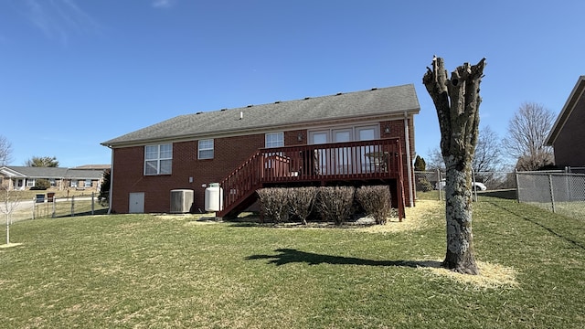 rear view of house featuring central air condition unit, a deck, a lawn, and brick siding