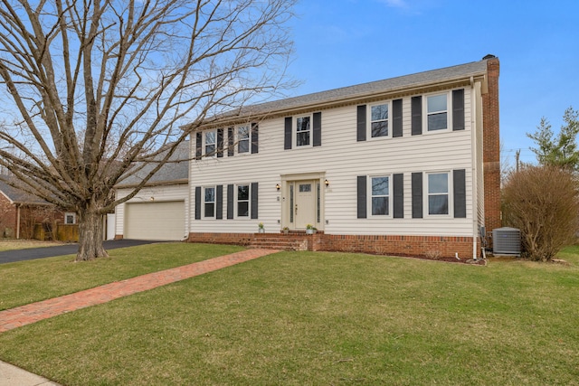 colonial house featuring central air condition unit, a front lawn, driveway, an attached garage, and a chimney