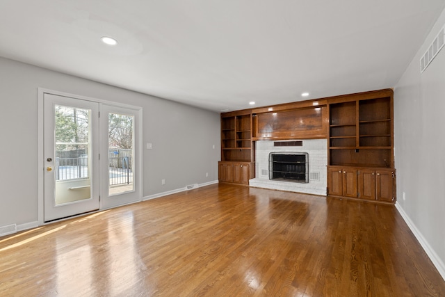 unfurnished living room with wood finished floors, visible vents, baseboards, a fireplace, and recessed lighting