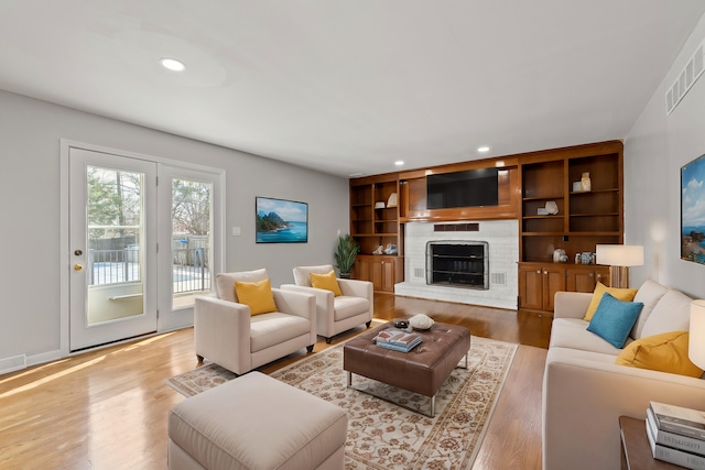 living room featuring visible vents, recessed lighting, a fireplace, and wood finished floors