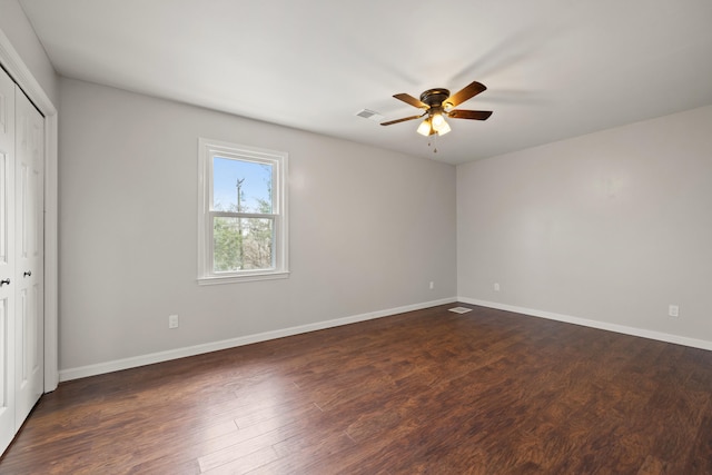 unfurnished bedroom with a ceiling fan, visible vents, baseboards, dark wood-style flooring, and a closet