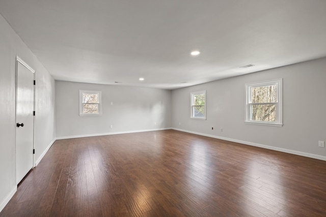 empty room featuring dark wood-style floors, visible vents, and a wealth of natural light