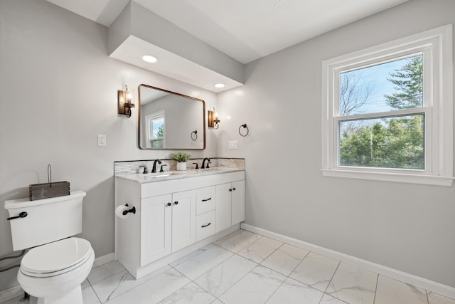 bathroom with toilet, baseboards, marble finish floor, and a sink