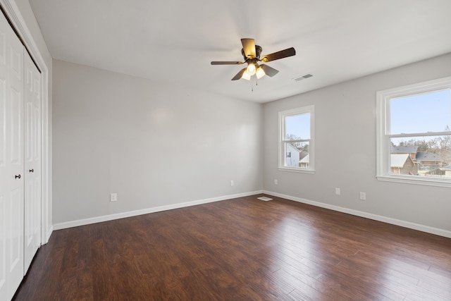 unfurnished bedroom featuring visible vents, ceiling fan, baseboards, a closet, and dark wood-style flooring