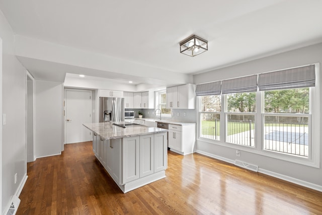 kitchen featuring visible vents, a center island, appliances with stainless steel finishes, wood finished floors, and white cabinets