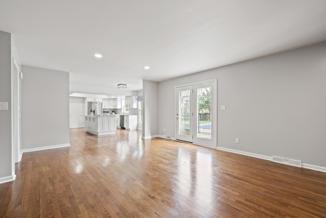 unfurnished living room with light wood finished floors, visible vents, recessed lighting, and baseboards