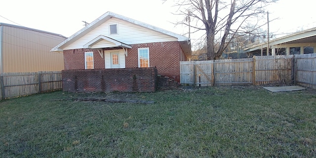 back of house featuring brick siding, a fenced backyard, and a yard