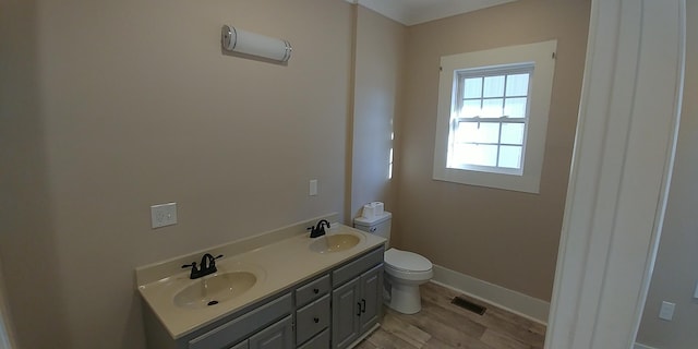 bathroom featuring visible vents, double vanity, a sink, and toilet