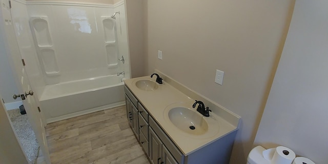 bathroom featuring double vanity, bathtub / shower combination, a sink, and wood finished floors