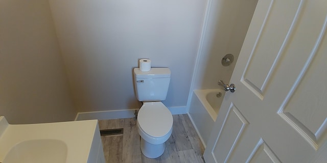 bathroom with visible vents, toilet, wood finished floors, a tub, and baseboards